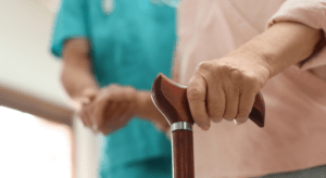 Nurse helping a patient to walk with the wooden walking stick.
