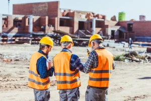 three workers are standing on the construction site and talking with each other